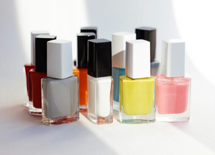 Varios frascos de esmalte de uñas de colores alineados sobre una superficie blanca