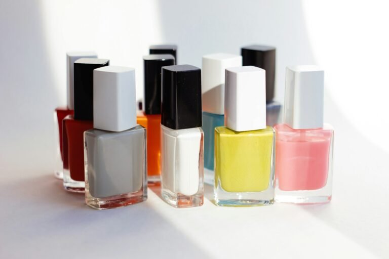 Varios frascos de esmalte de uñas de colores alineados sobre una superficie blanca