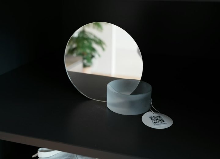 A round mirror on a shelf with a tag