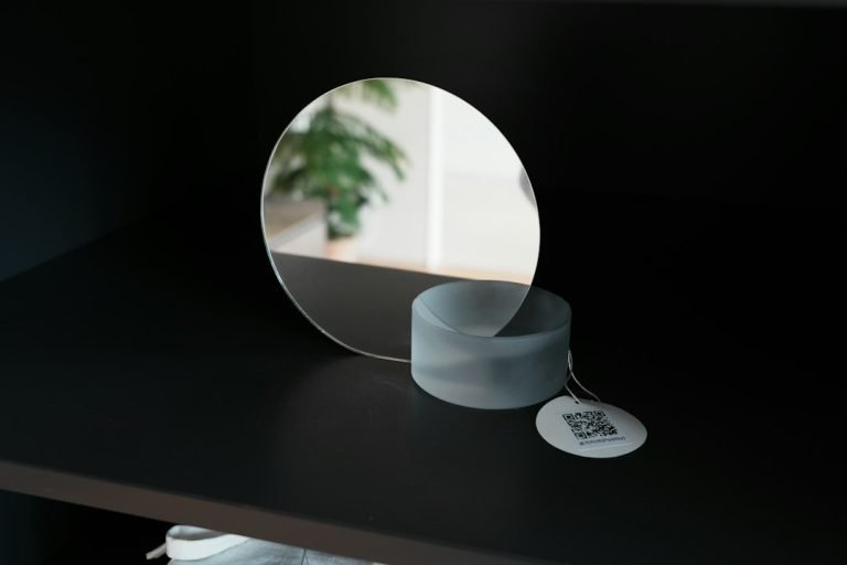 A round mirror on a shelf with a tag