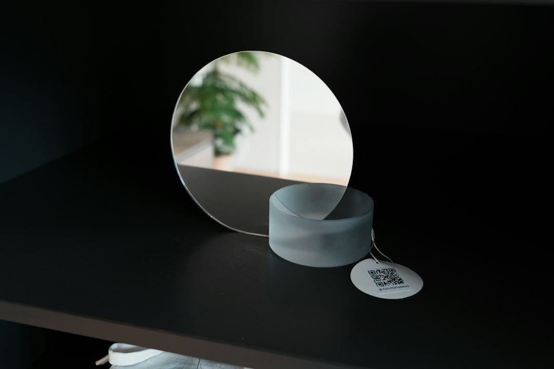 A round mirror on a shelf with a tag